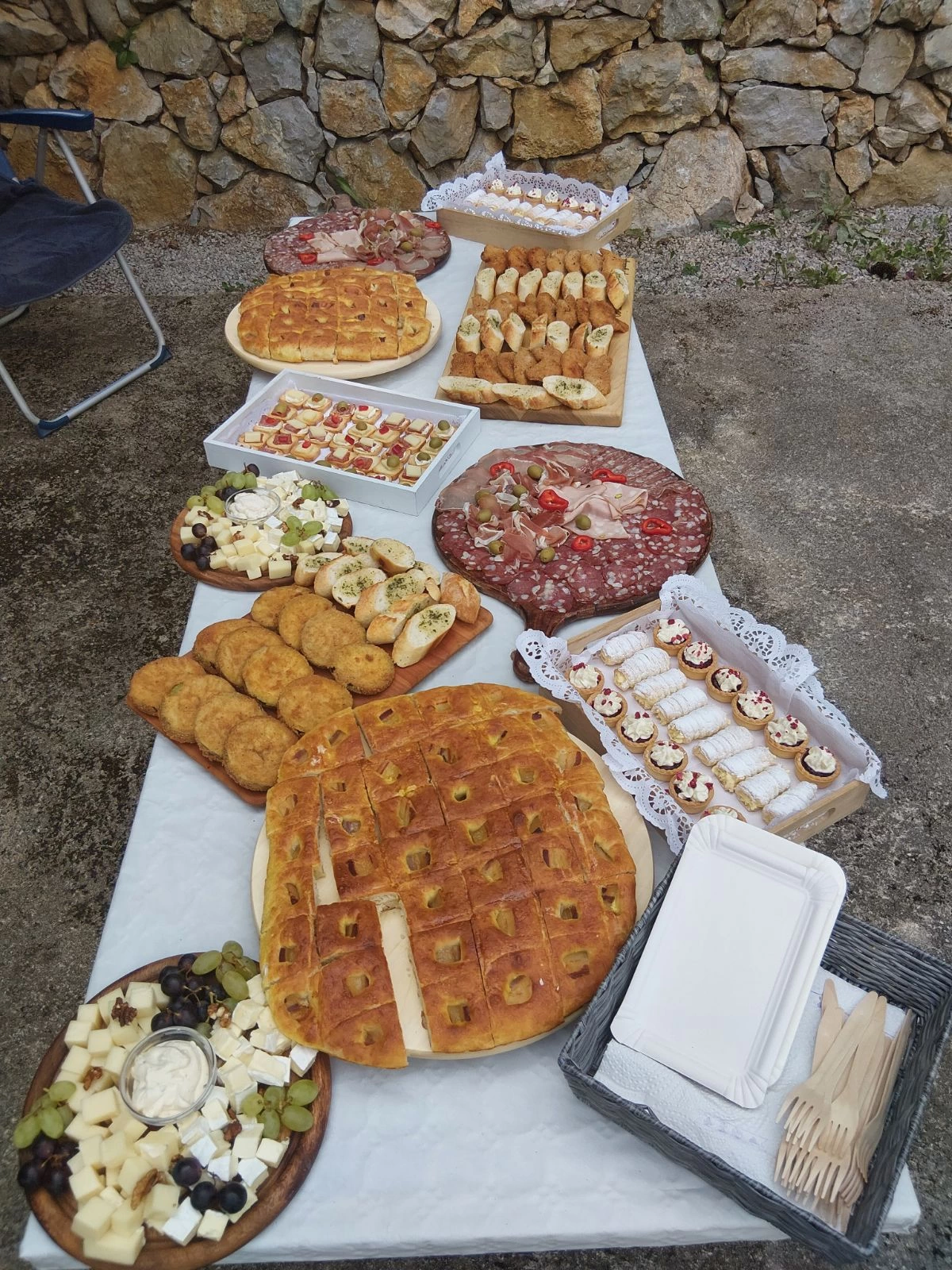 Bogato pogrnjena miza z narezki, sirom, pecivom in slaščicami