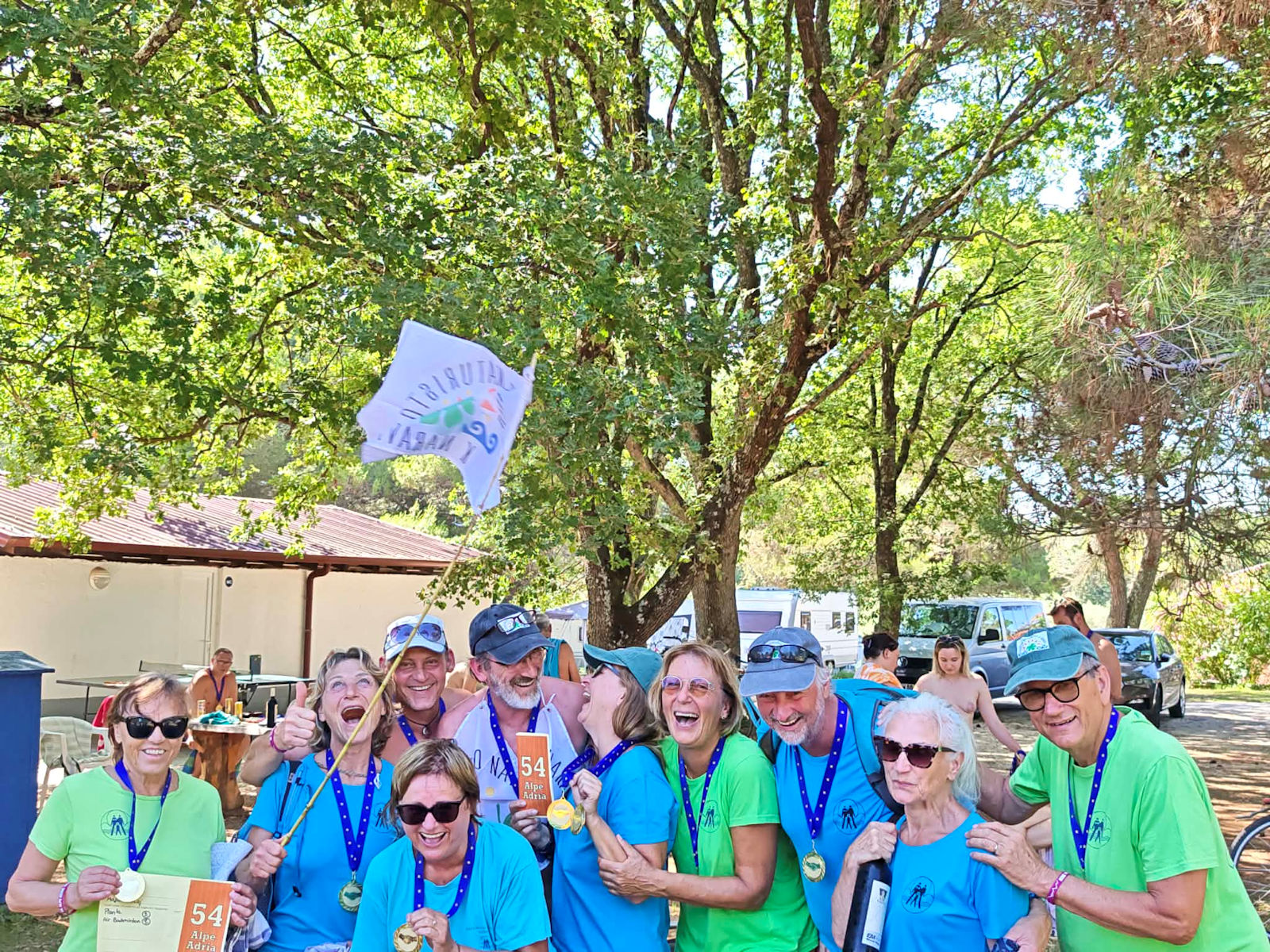 Ekipa Društva naturistov k naravi z medaljami in zastavo društva na igrah Alpe-Adria