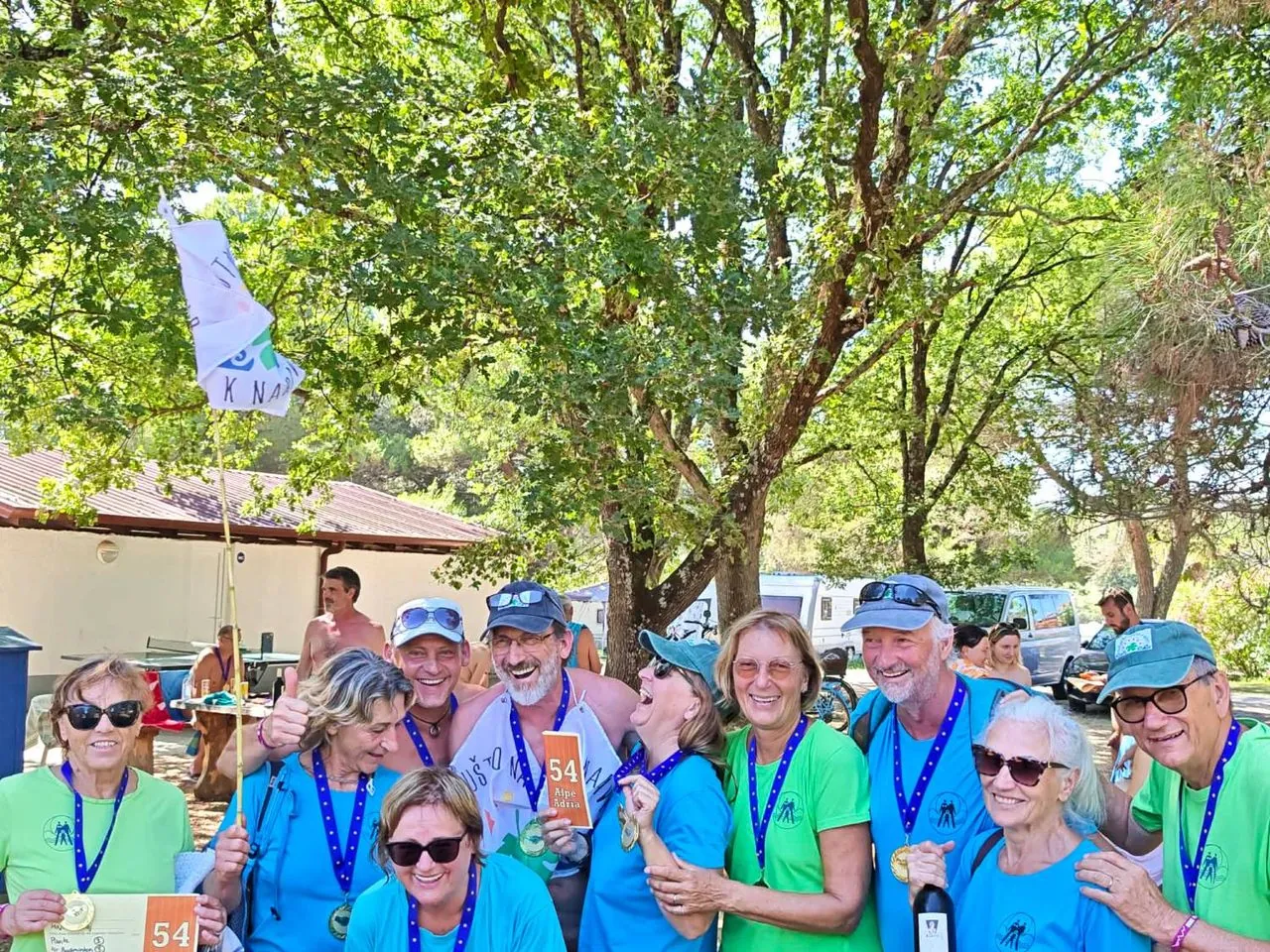 Members of the K naravi club posing with medals and the club flag at the Alpe-Adria Games