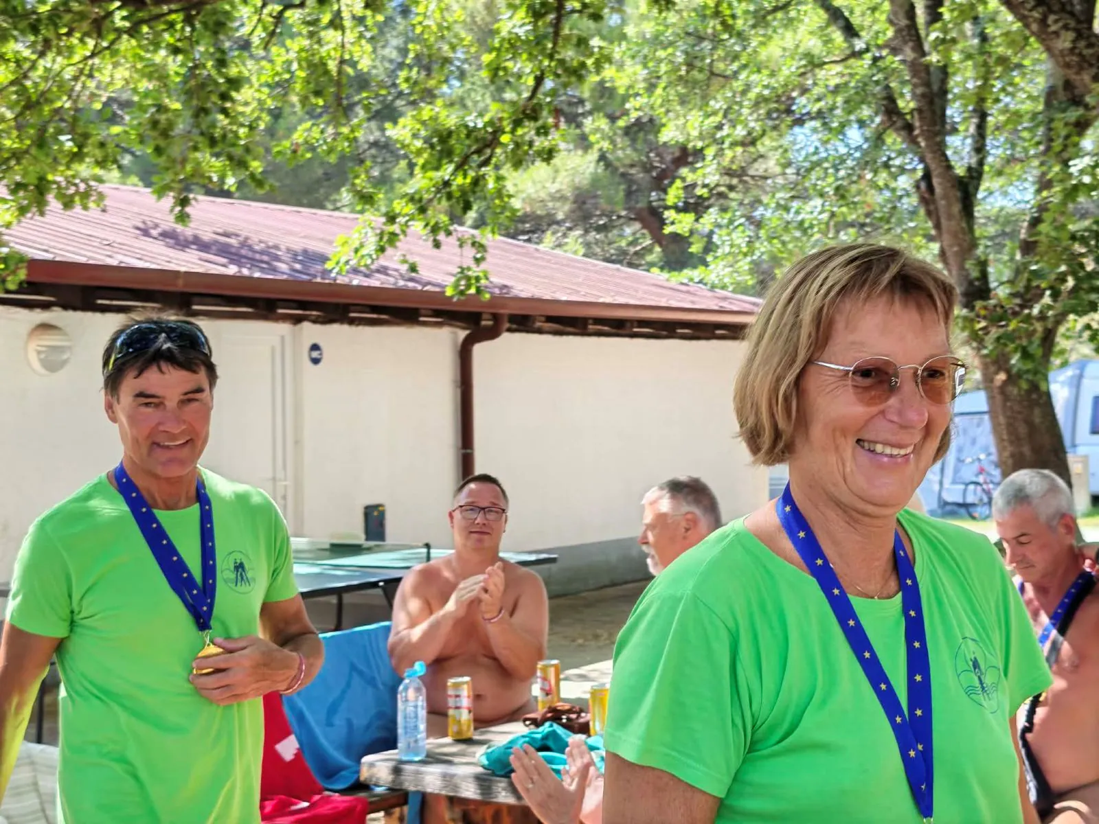 Moški in ženska z zelenima medaljama ob mizi za namizni tenis